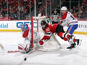 Skating in his first NHL game, Canadiens' Rinat Valiev checks Devils' Blake Coleman behind the net as goalie Charlie Lindgren looks on Tuesday night in Newark, N.J.