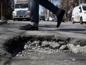A pedestrian walks by a massive pothole on St-Viateur and de l' Esplanade in Montreal on Tuesday March 29, 2016.