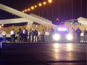 Police lights illuminate the scene of a pedestrian bridge collapse in Miami, Florida on March 15, 2018, crushing a number of cars below and leaving several people dead.