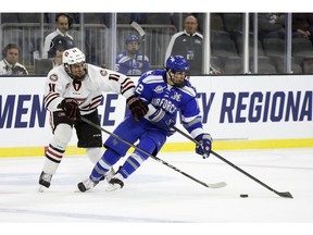 St. Cloud State's Ryan Poehling grabs the arm of Air Force's Matt Serratore during the first period of an NCAA regional tournament game on March 23, 2018, in Sioux Falls, S.D.