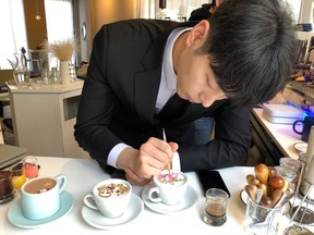 In this March 1, 2018, photo, Barista Lee Kang Bin applies the finishing touches to a recreation of a couple's Niagara Falls vacation photo, at his coffee shop in Seoul, South Korea. The South Korean barista is charming customers at his coffee shop by drawing intricate artworks on the foamy cream toppings of their drinks.