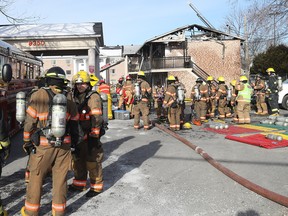 Firefighters clear debris after a fire an Econolodge in Brossard March 21, 2018.