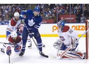 Maple Leafs' James van Riemsdyk (centre) tries to tip the puck past Canadiens goaltender Charlie Lindgren as Montreal defenceman Jordie Benn (left) defends during second period NHL hockey action in Toronto on Saturday, March 17, 2018.