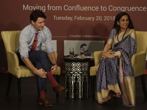 Canadian Prime Minister Justin Trudeau, left, tries to adjust his socks as ICICI bank CEO Chanda Kochhar looks on during Canada India Mumbai Business form in Mumbai, India, Tuesday, Feb. 20, 2018.