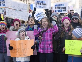 Eleven year old, Lexington Vickery, third from left, holds up signs during a 'March for Our Lives' rally to show solidarity with the U.S. gun control movement in Montreal, Saturday, March 24, 2018.