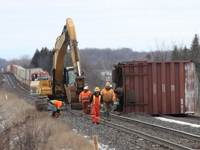 A CN crew works on an overturned freight train car just east of Kingston, Ont. on Saturday, March 3, 2018. All train traffic on the line has been halted.