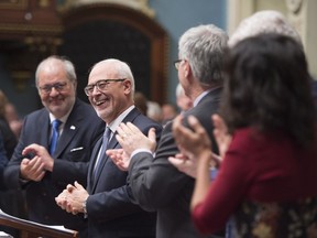 Quebec Finance Minister Carlos Leitao is applauded by members of the government as he stands to present his budget speech, Tuesday, March 27, 2018 at the National Assembly in Quebec City. Quebec Treasury Board president Pierre Arcand, left, applauds.