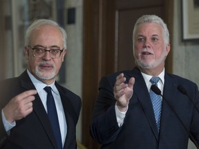 Quebec Premier Philippe Couillard, right, and Quebec Finance Minister Carlos Leitão respond to reporters' questions at the National Assembly in Quebec City, Wednesday, March 14, 2018.