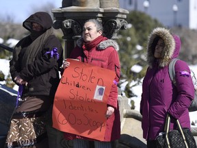 Sixties Scoop survivor Brenda Zonruiter, centre, holds a sign with a photo of herself as a child during a national solidarity rally called by the National Indigenous Survivors of Child Welfare Network on Parliament Hill in Ottawa on Friday, March 16, 2018.