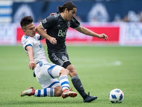 Impact's Ken Krolicki, left, slides to tackle Whitecaps' Efrain Juarez during the first half in Vancouver on Sunday, March 4.