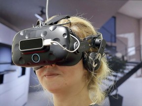 A woman wears virtual reality glasses at a tech fair. in Berlin, Germany, Wednesday, Aug. 30, 2017.