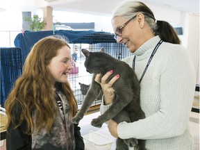 CASCA volunteer Lucie Chabot, right, shows Emma Boardman newly adopted cat, Rio, during a clinic in Pincourt on Saturday.