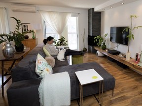Pina Tamburro reads in the living room of her Anjou home. "I had actually wanted to take down the wall the TV is mounted on," Pina Tamburro said, but "the contractor installed the low shelf to make a focal point for the room and built a fireplace in the corner."