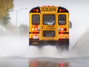 A school bus kicks up water spray as it merges with traffic on Highway 20 at the eastbound 55th Ave. on-ramp in Montreal Tuesday Oct. 24, 2017.
