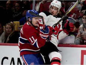 Canadiens' Brendan Gallagher drives New Jersey Devils defenceman John Moore into the boards in Montreal on Sunday, April 1, 2018.