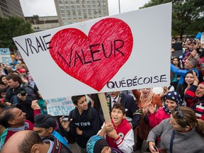 A boy holds a poster as protesters take part in a demonstration opposing the proposed Charter of Quebec Values in downtown Montreal on Saturday, September 14, 2013.