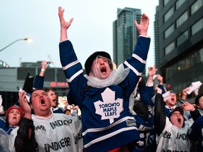 Fans react while watching sport action on large TV screens at Maple Leaf Square in Toronto Wednesday, April 25, 2018. Still reeling from Monday's deadly van attack, hundreds of Torontonians braved the rain outside Air Canada Centre on Wednesday night to cheer on three of the city's teams as they play in pivotal games.