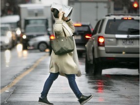 A pedestrian uses a newspaper as an umbrella while crossing Sherbrooke St.