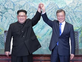 North Korean leader Kim Jong Un, left, and South Korean President Moon Jae-in raise their hands after signing on a joint statement at the border village of Panmunjom in the Demilitarized Zone, South Korea, Friday, April 27, 2018. (Korea Summit Press Pool via AP) ORG XMIT: XSEL156