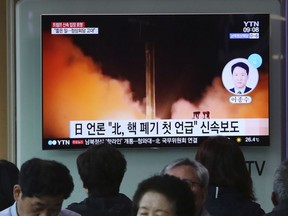 People watch a TV screen showing a file footage of North Korea's missile launch during a news program at the Seoul Railway Station in Seoul, South Korea, Saturday, April 21, 2018. North Korea said Saturday it has suspended nuclear and long-range missile tests and plans to close its nuclear test site. The announcement came ahead of a new round of nuclear negotiations between Pyongyang, Seoul and Washington, but there was no clear indication in the North's announcement if it would be willing to deal away its arsenal. The signs read: "Japanese media reports North Korea says it has suspended nuclear and long-range missile tests."