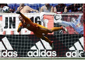 Montreal Impact goalkeeper Evan Bush dives to deflect a shot from the New York Red Bulls during the first half of a soccer match on Saturday, April 14, 2018, in Harrison, N.J.