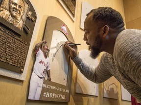 Vladimir Guerrero signs the spot where his Baseball Hall of Fame plaque will hang during a visit to the hall, Thursday, April 26, 2018, in Cooperstown, N.Y. Guerrero, a native of the Dominican Republic, was elected to the Hall of Fame in January. He played sixteen seasons in the major leagues with the Montreal Expos, Los Angeles Angels of Anaheim, Texas Rangers and Baltimore Orioles.