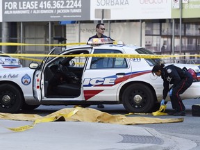 Police officers secure an area around a covered body in Toronto after a van mounted a sidewalk crashing into a number of pedestrians on Monday, April 23, 2018.