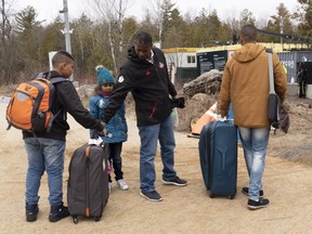 A family, claiming to be from Colombia, gets set to cross the border into Canada from the United States as asylum seekers on Wednesday, April 18, 2018 near Champlain, N.Y.