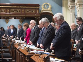 Quebec Premier Philippe Couillard, right, is joined by members of the legislature on Tuesday for a moment of silence in memory of victims of the incident in Toronto where a van struck and killed pedestrians on Monday.