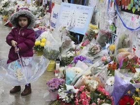 A steady stream of people stop to drop off flowers and read handwritten notes at a memorial wall at Yonge St and Finch Ave. on Wednesday April 25, 2018 after the deadly van attack in North York.