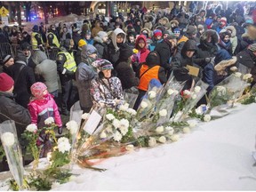 People place flowers after a vigil at the Centre culturel islamique de Quebec marking the first anniversary of the fatal mosque shooting Monday, January 29, 2018 in Quebec City.