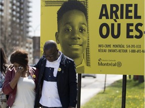 Akouena Noëlla Bibie and her husband, Kouadio Frédéric Kouakou, are seen near billboard for their missing son, Ariel Jeffrey Kouako, in Montreal on Wednesday May 9, 2018.