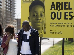 Akouena Noëlla Bibie and her husband, Kouadio Frédéric Kouakou, are seen near a billboard for their missing son, Ariel Jeffrey Kouako, in Montreal on Wednesday May 9, 2018.