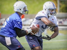 Running-back William Stanback, right, fakes taking a handoff from quarterback Antonio Pipkin during Montreal Alouettes' training camp practice in Montreal on Thursday, May 24, 2018.