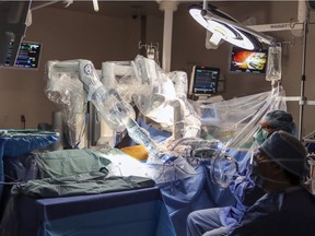 Operating room staff watch as robotic arms, controlled by surgeon Emmanuel Moss, not shown, perform cardiac surgery at the Jewish General Hospital in Montreal on Monday, May 28, 2018.