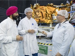 From left, Navdeep Bains, Minister of Innovation, Science and Economic Development, CSA astronaut Jeremy Hansen and MDA President Mike Greenley speak next to a RADARSAT Constellation satellite following a funding announcement in Ste-Anne-de-Bellevue on May 25. (Graham Hughes/Montreal Gazette)