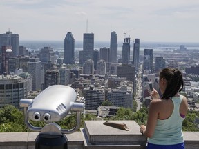 A woman takes a photo of the Montreal skyline from the Mount Royal lookout on Monday, June 20, 2016.