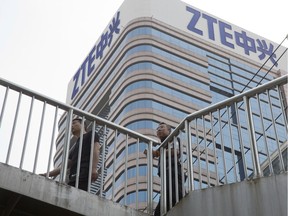 In this May 8, 2018, photo, Chinese men pass by a ZTE building in Beijing, China. President Donald Trump's weekend social media musings about China injected new uncertainty into the Washington's punishment of Chinese tech giant ZTE and planned trade talks between the two countries.