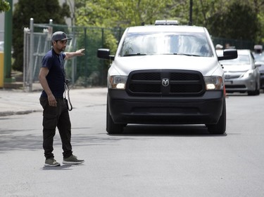 MONTREAL, QUE.: MAY 23, 2018-- A parking lot worker walks out into Notre-Dame Street forcing traffic to stop to allow vehicles to enter the VIP parking area during the C2 event in Montreal on Wednesday May 23, 2018. (Allen McInnis / MONTREAL GAZETTE) ORG XMIT: 60727