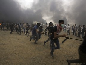 Palestinian protesters pull out the fence of the border after they burnt tires during a protest at the Gaza Strip's border with Israel, east of Khan Younis, Friday, May 4, 2018. When Genevieve Boutin and her colleagues at the United Nations Children's Fund were finished verifying the aftermath of this past week's carnage at the Gaza-Israel fence, they added seven more to their tally of dead children.