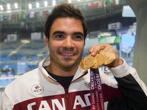 Canada's Alexandre Despatie holds up his three gold medals for diving at the 2010 Commonwealth Games in New Delhi, India.