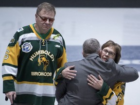 Humboldt Broncos team president Kevin Garinger, centre, hugs Humboldt Broncos athletic therapist Dayna Brons's mom Carol Brons as dad Lyle looks on prior to a ceremonial puck drop before the Memorial Cup semifinal action between the Hamilton Bulldogs and the Regina Pats in Regina on Friday, May, 25, 2018.