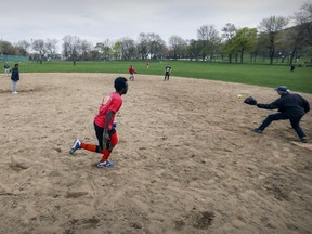 Mumin Ismail is thrown out at first base after hitting a ground ball during the weekly Wednesday night pick-up softball game on the north diamond at Jeanne Mance Park in Montreal Wednesday May 10, 2017.  The diamond was shut down to make way for construction equipment used to resurface nearby tennis courts, upsetting locals who used the diamond regularly in the nice weather.