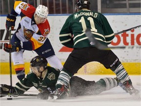 London Knights defenceman Evan Bouchard is careful not to put his hand on the puck near Erie's Warren Foegele and Knights' Owen MacDonald during OHL playoff series in London, Ont., on April 11, 2017.