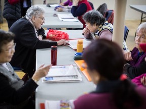 Violet Campbell, back left, helps Wu Xiao Yun, back right, during a weekly group meeting to help people practice their English skills, combat social isolation and foster relationships, in Vancouver, B.C., on Friday February 23, 2018. The problem of social isolation, which can have serious consequences on a person's mental health and mortality, gained international awareness when the United Kingdom appointed a minister of loneliness in January.