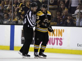 In this May 2, 2018, photo, Boston Bruins' Brad Marchand is escorted to the penalty box during the second period of Game 3 of an NHL second-round hockey playoff series against the Tampa Bay Lightning in Boston. The NHL has told  Marchand to stop licking opponents or the Bruins forward will face punishment.