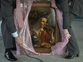 FBI agents unwrap "Young Man As Bacchus" by Jan Franse Verzijl before before the start of a ceremony to formally return the painting to representatives of the Max and Iris Stern Foundation, Wednesday, Feb. 8, 2017, at the Museum of Jewish Heritage in New York.