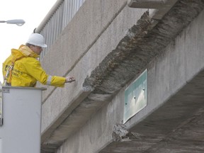 A Transport Quebec worker inspects Hymus overpass at Highway 40, where a piece of concrete fell off, in this January 2014 file photo.