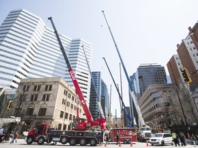Crane operators raise the arms of their cranes on the street during a protest in Montreal on Saturday, May 5, 2018.