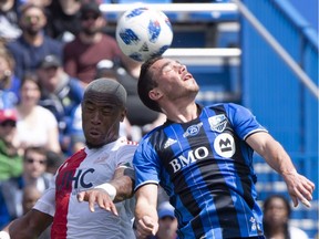 Impact defender Daniel Lovitz, right, heads the ball away from New England Revolution defender Claude Dielna during first half MLS action on May 5, 2018, in Montreal.